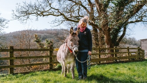 A women stood with a donkey in an outside paddock