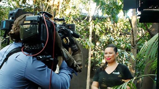 A behind the scenes view of a cameraman filming a women