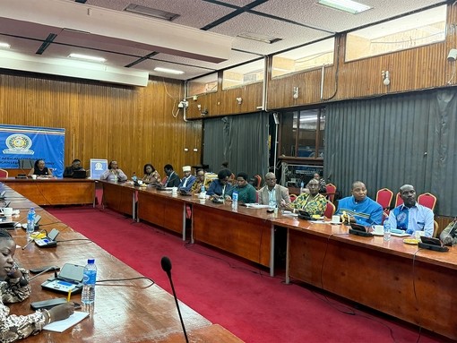 A conference room filled with people sitting at a long U shape desk